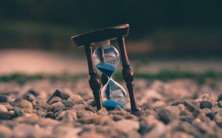 selective focus photo of brown and blue hourglass on stones