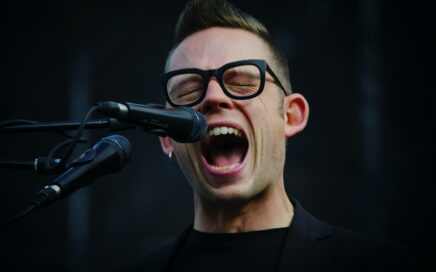 shallow focus photography of man shouting using microphone