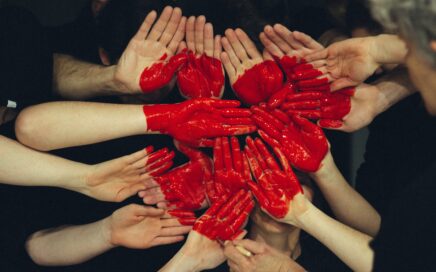 hands formed together with red heart paint