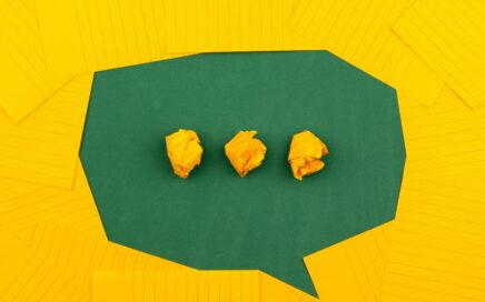 three crumpled yellow papers on green surface surrounded by yellow lined papers