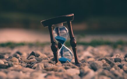 selective focus photo of brown and blue hourglass on stones