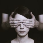 person covering the eyes of woman on dark room