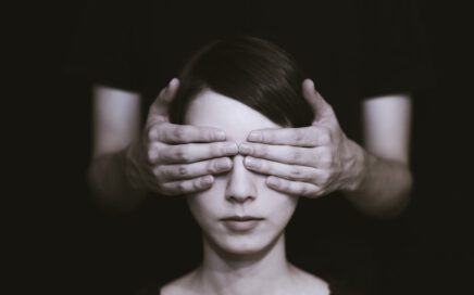 person covering the eyes of woman on dark room