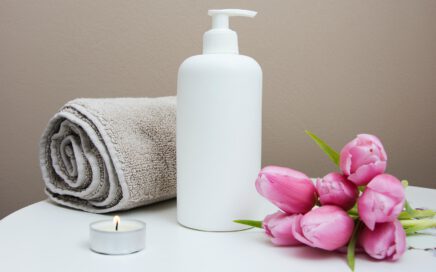 white plastic pump bottle beside pink tulips and gray towel