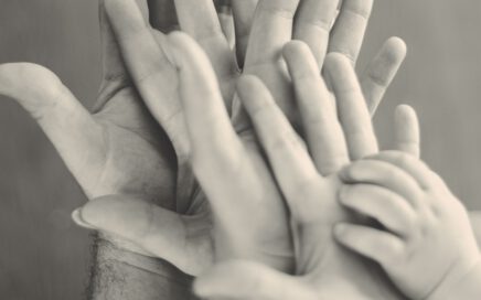 grayscale photo of family's hands