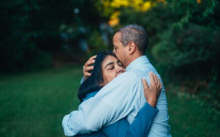 man hugging woman near trees