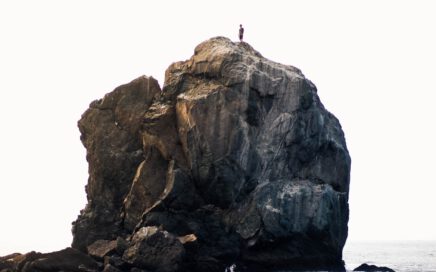 person standing on rock near ocean during daytime