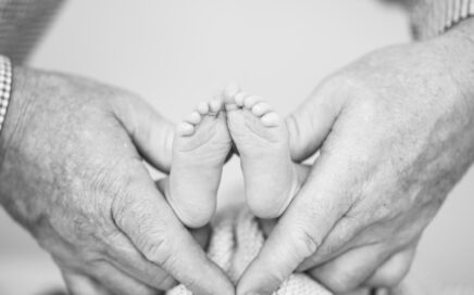 grayscale photography of person holding newborn's feet