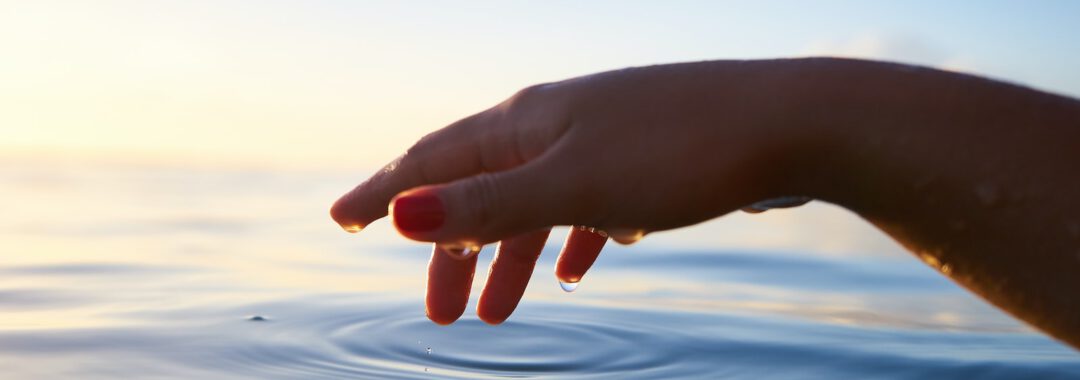 person about to touch the calm water
