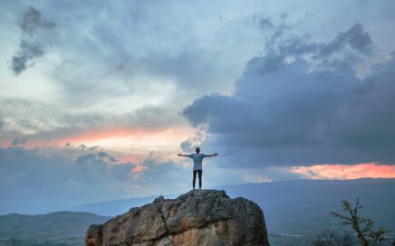 man standing on top of rock mountain during golden hour