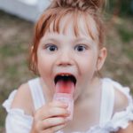 girl licking jar selective focus photography