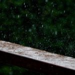 a wooden bench with rain falling down on it